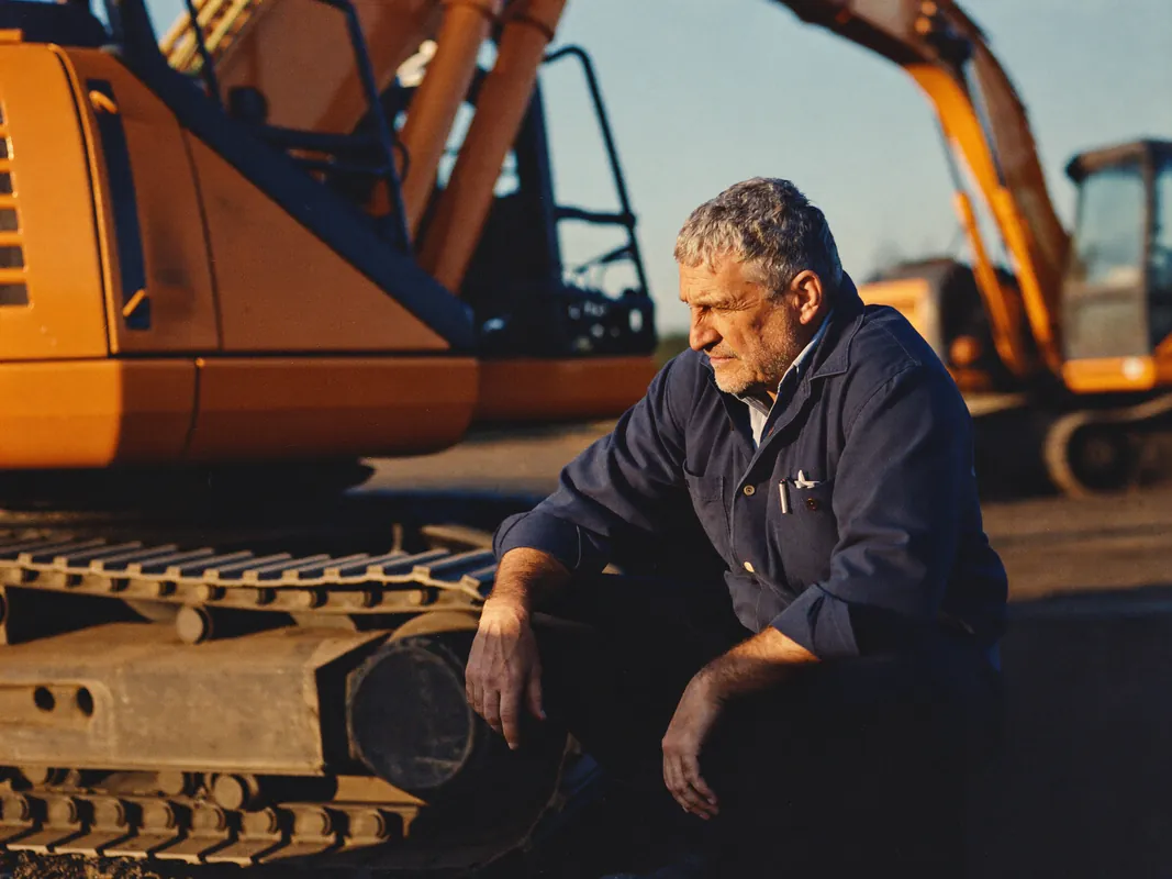 AI concept image: an equipment dealer inspecting the tracks of a newly delivered excavator